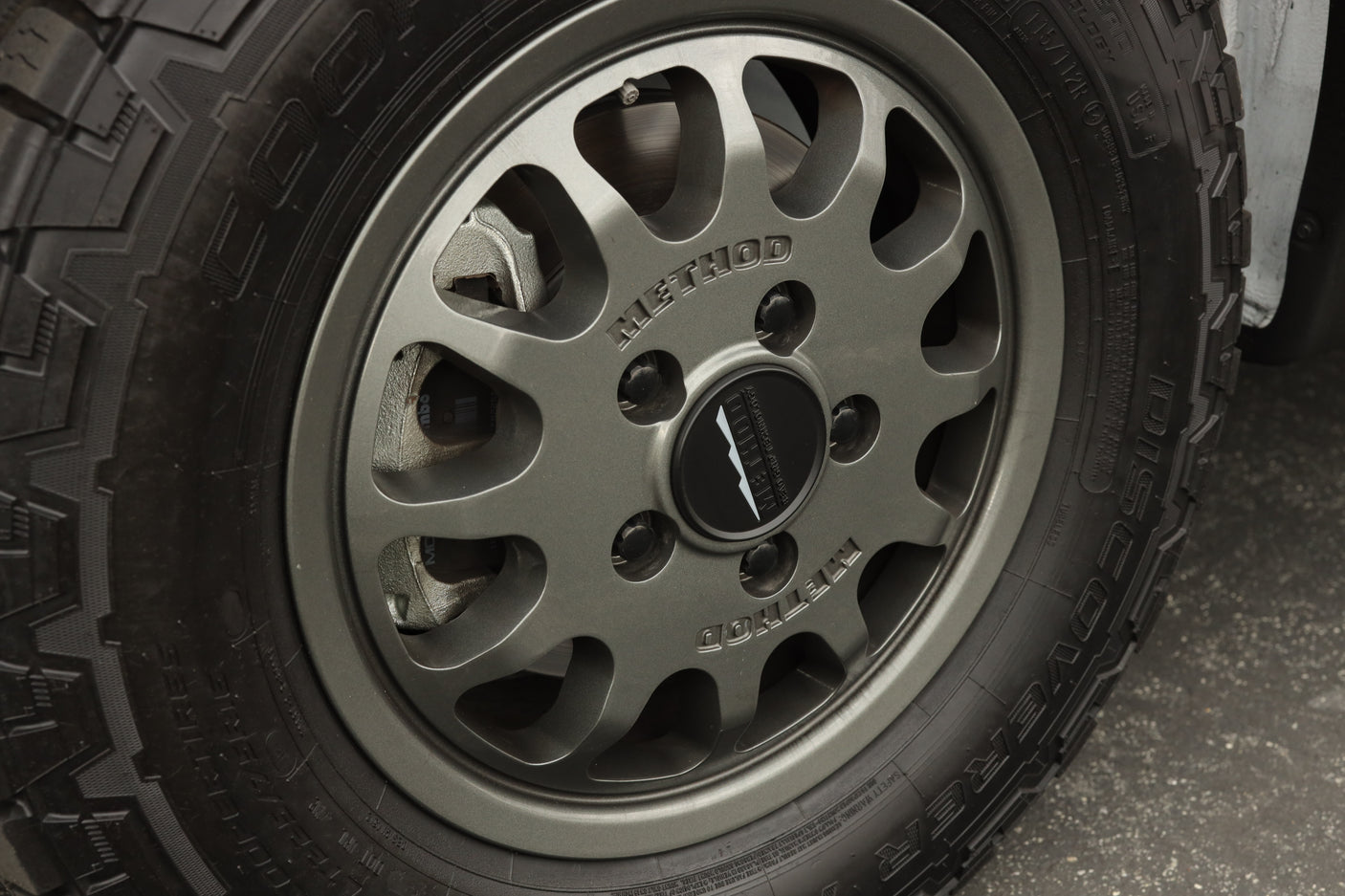 Close-up of a rugged Cooper Discoverer tire and Method wheel with Brembo brakes, ideal for an RV rental adventure.