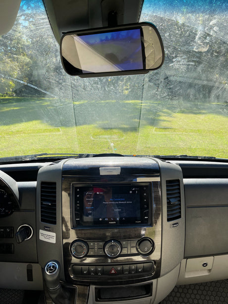 RV rental interior: driver's view of a streaky windshield, rearview camera screen, and dashboard with FUSION infotainment.