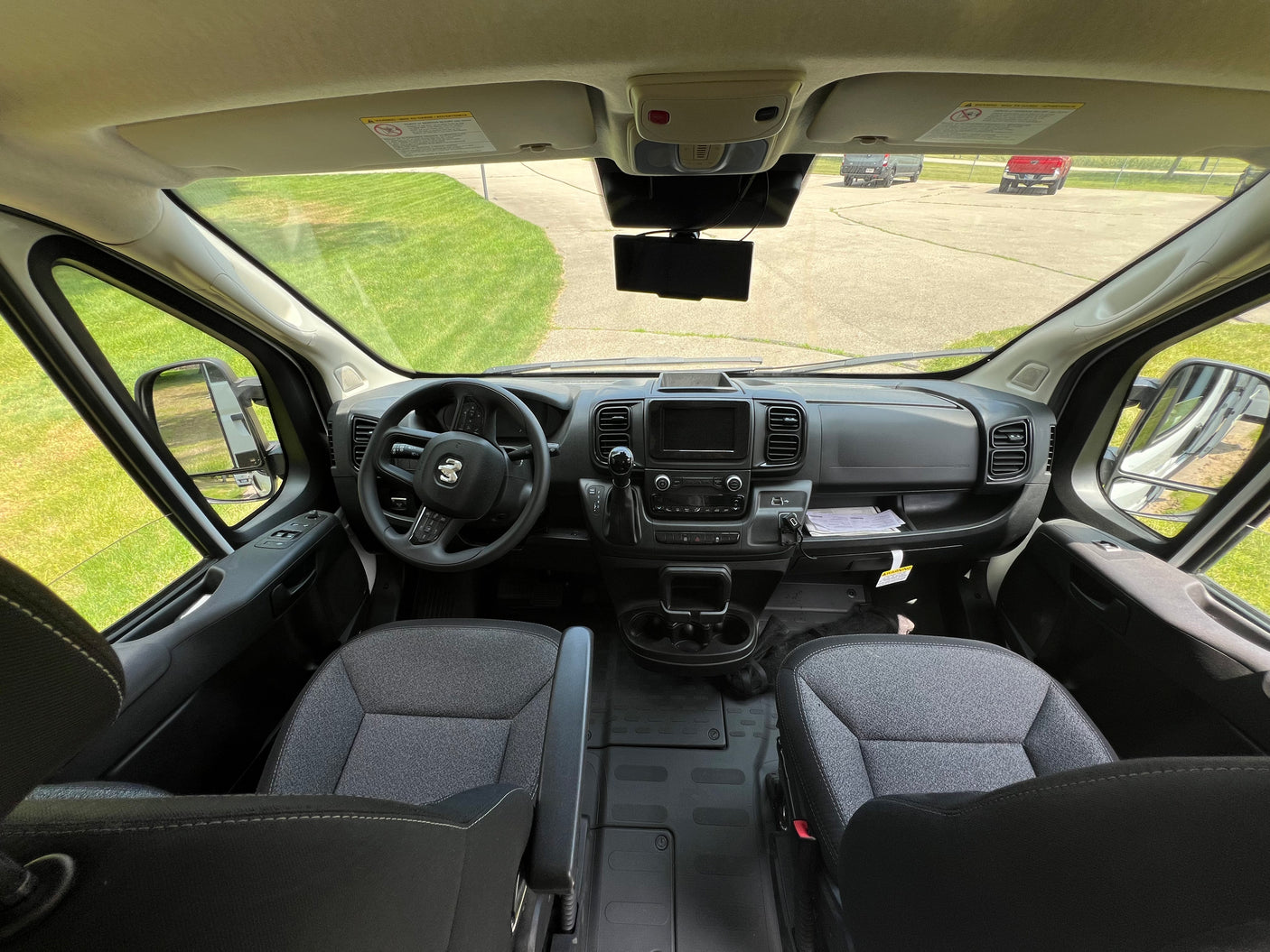 Spacious RV rental cabin: driver's view of the dashboard, steering wheel, seats, and clear road ahead.