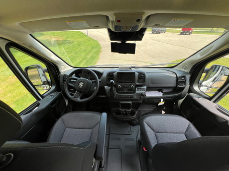 Spacious RV rental cabin: driver's view of the dashboard, steering wheel, seats, and clear road ahead.