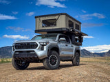 Silver Toyota Tacoma truck with a large Tune Outdoor rooftop tent