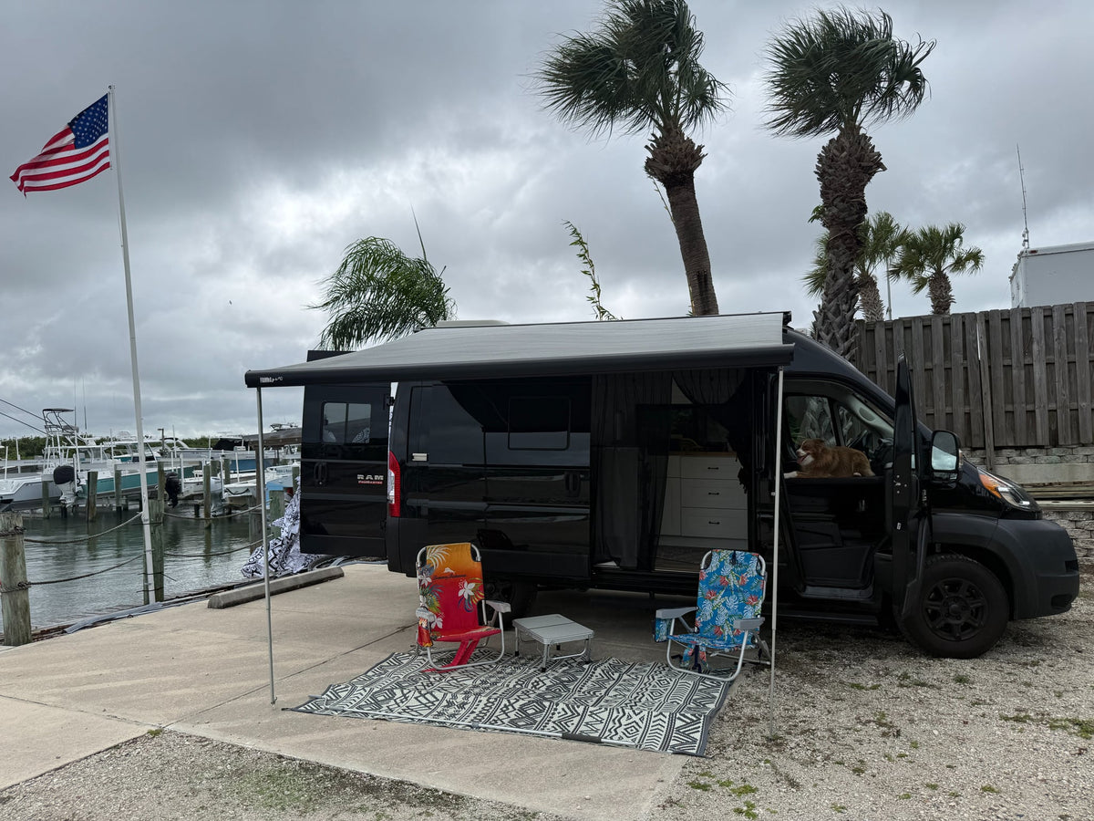 Black RV rental parked dockside with awning — photo 1