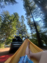 Hammock chill with a book by an SUV in the forest. Enjoying nature's peace; no rv rental needed for this camping escape.