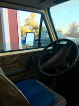Driver's view from an RV rental, featuring steering wheel, dashboard, and autumn outdoor scenery including a barn.