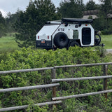 This white XTR overland trailer, equipped with a bike and awning, is perfect for an RV rental adventure.