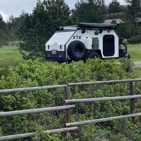 This white XTR overland trailer, equipped with a bike and awning, is perfect for an RV rental adventure.