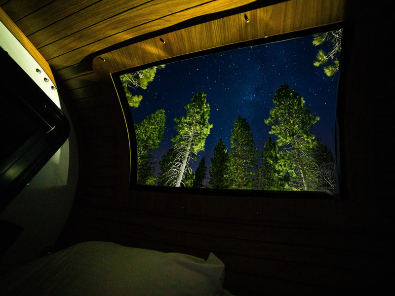 Cozy rv rental interior with a stunning night sky view through the window, featuring starry skies and illuminated pine trees. — photo 13