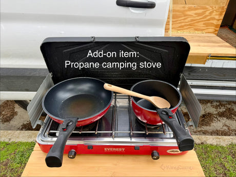 RV rental add-on: Red propane camping stove with pan and pot on a wooden table, ready for outdoor cooking.