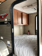 Step inside this Retro Jr. RV rental interior: a comfy bed, wood cabinets, and AC, ready for your next adventure.