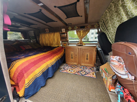 Cozy RV rental interior with a bed, wooden cabinet, and clever storage solutions, ideal for adventurous travel.