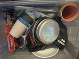 RV rental kitchen kit: foil, mugs, pots, flatware, & plates packed for convenience in a clear bin.