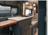 This rv rental features a well-equipped kitchenette: sink, faucet, counter, drawers, and an extendable wooden shelf.