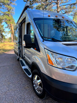 This silver camper van, ideal for RV rental adventures, is parked outdoors with its side door open, ready for travel.