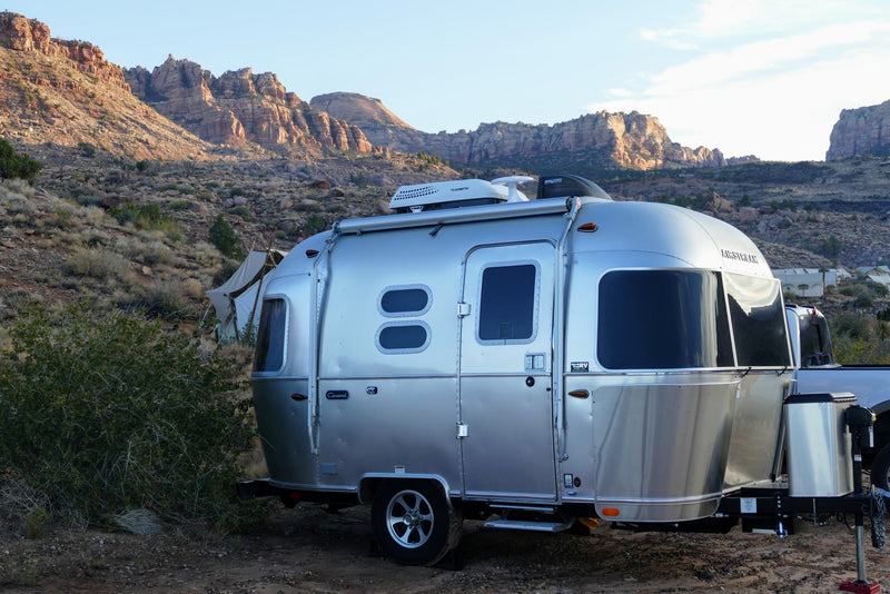 Silver Airstream RV rental parked in a scenic desert landscape with towering rocky mountains and other glamping tents. — photo 3