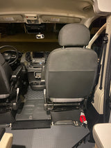 Experience the interior of this rv rental. Driver's cockpit view shows dashboard, steering, seats, and fire extinguisher.