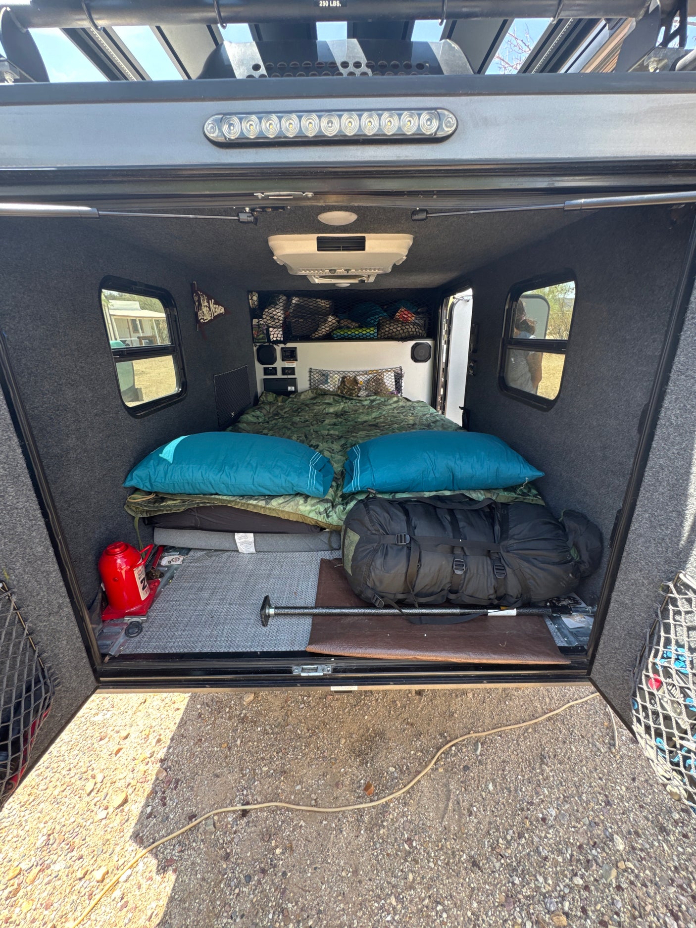 Cozy RV rental: interior with bed, overhead AC, and organized gear for camping trips.