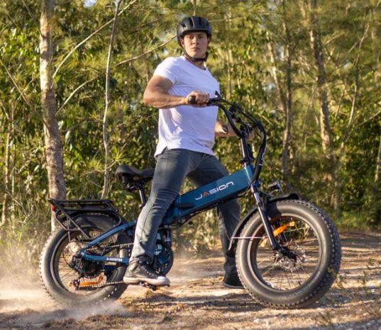 Man in helmet on a teal Jasion fat-tire e-bike on a dusty path. Explore new trails with your RV rental.