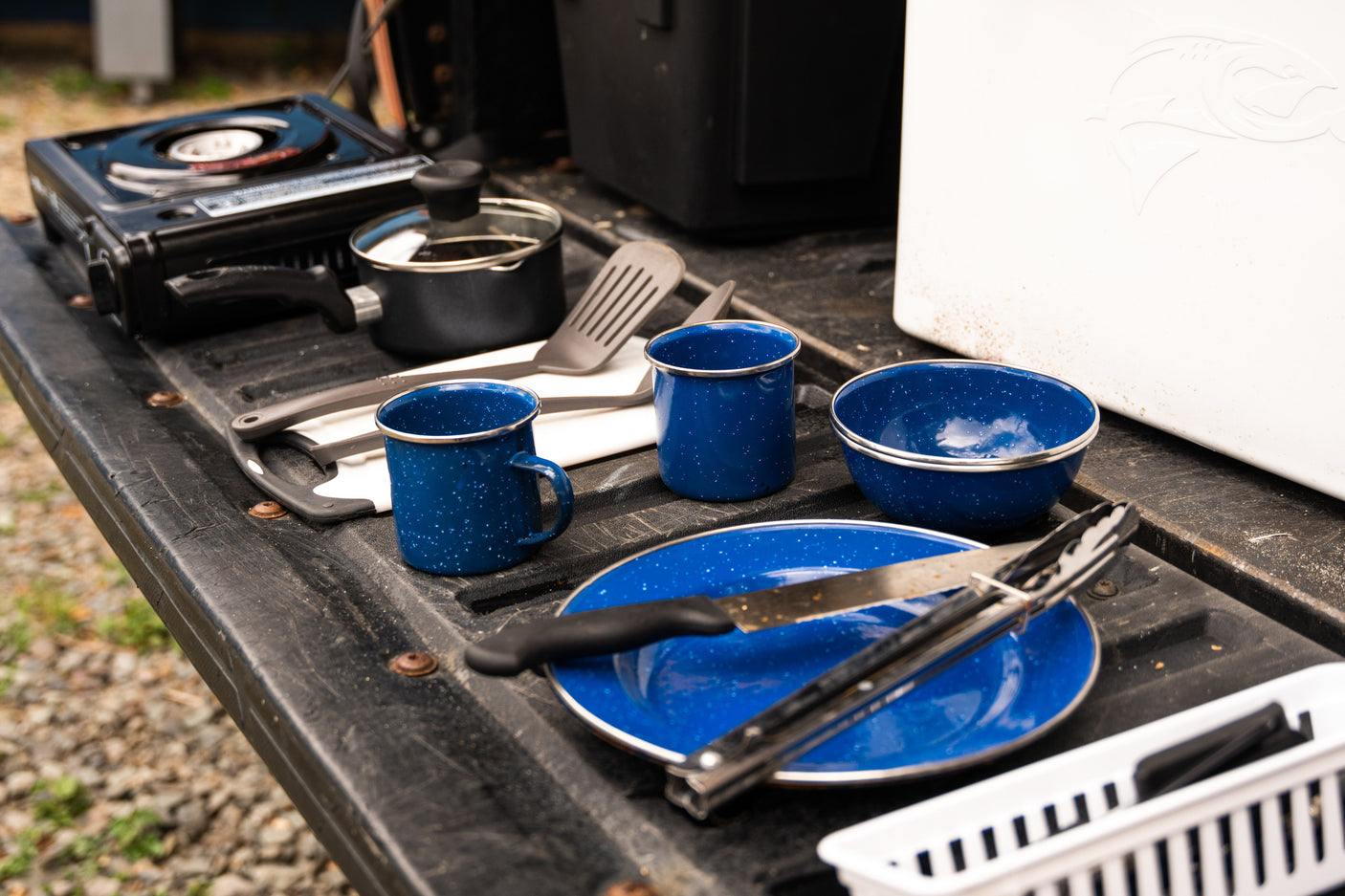 RV rental outdoor kitchen setup: Camping cookware, stove, and cooler on a truck bed, ready for adventure.