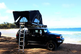Explore with this RV rental: A Toyota FJ Cruiser with a rooftop tent ready for beach camping.