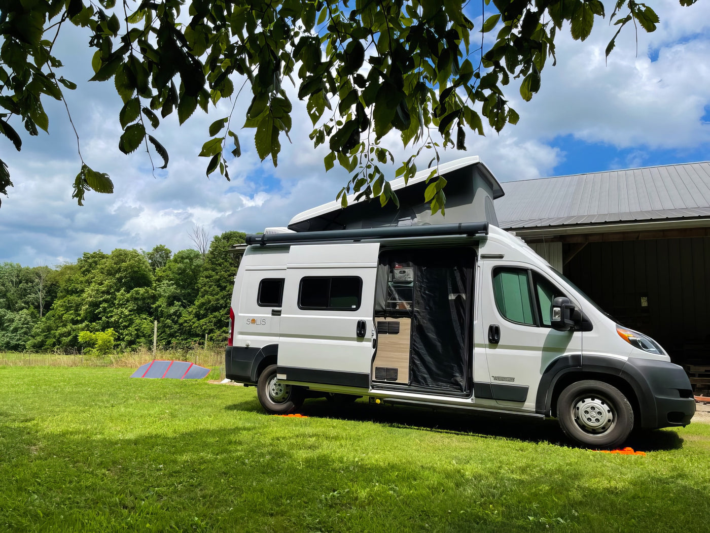 White pop-top camper van, side door open, parked on green grass under leafy trees. Perfect for your next RV rental adventure. — photo 17