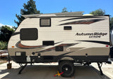 Side view of an Autumn Ridge Extreme travel trailer, parked on concrete. This RV rental is ready for adventure under a clear sky.