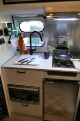 Compact RV kitchen, ideal for an rv rental, featuring a sink, stove, microwave, and refrigerator for cooking on the go.