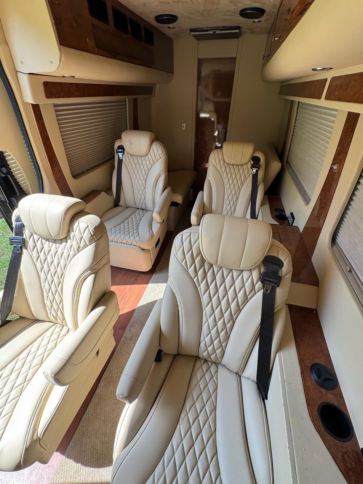 Spacious luxury rv rental interior featuring cream diamond-quilted seats, wood accents, and amenities for comfortable travel.