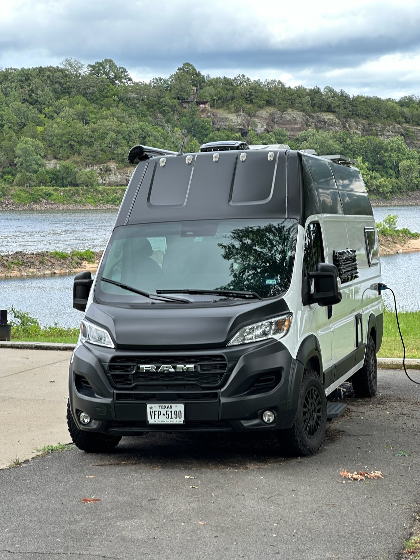 This rv rental camper van is parked by a lake, plugged in and ready for adventure. Enjoy nature in this converted Ram ProMaster. — photo 15