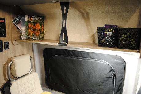 RV rental interior: A light wood shelf holds travel guidebooks & storage baskets, with controls nearby.