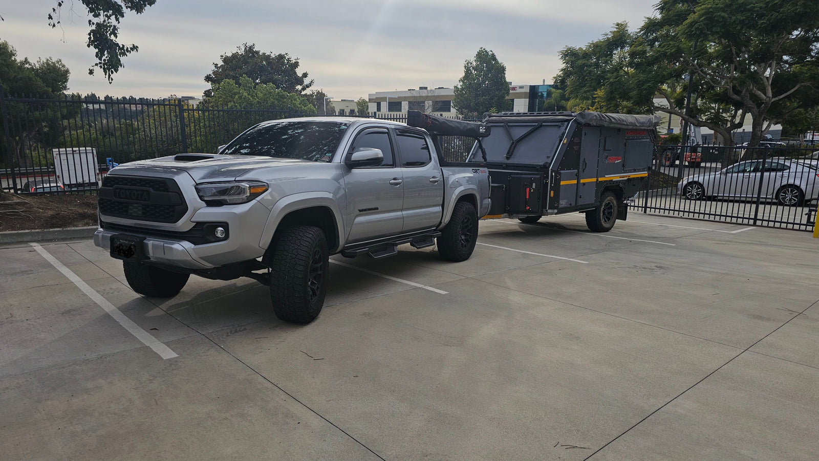 Silver Toyota Tacoma towing a rugged Conqueror off-road camper trailer, an ideal setup for an RV rental adventure.
