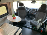 RV rental interior: Front cabin with swiveling seats, a small table with fruit, and a comfortable rear seating area.