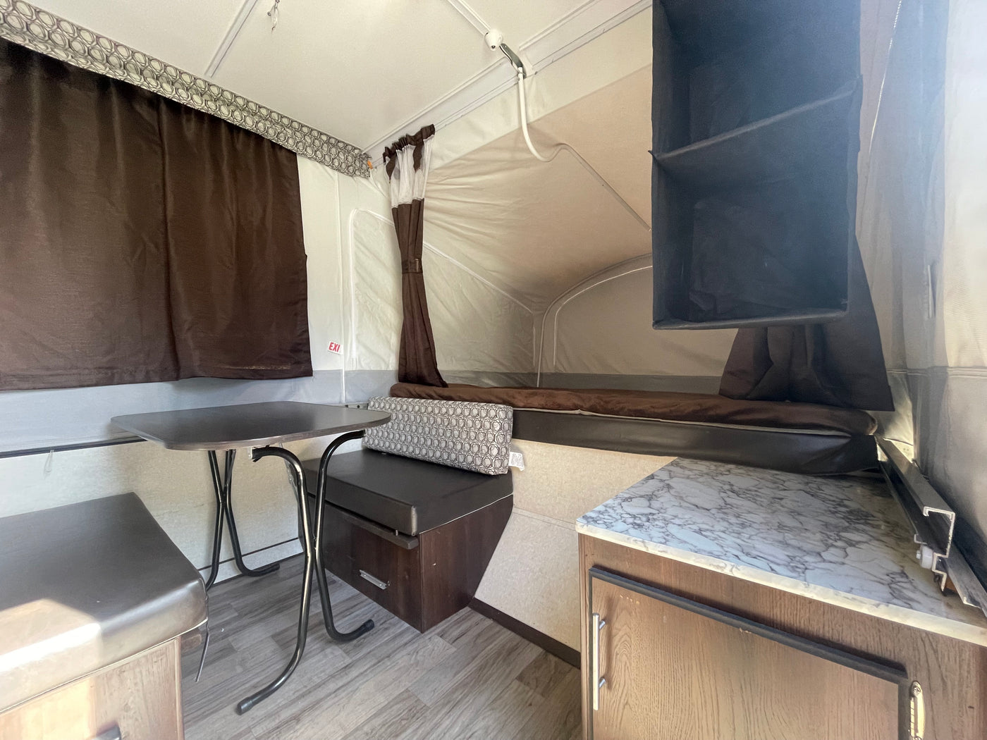 Interior of an RV rental pop-up camper, featuring a dining nook, bed, and compact kitchen area. — photo 6