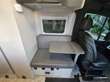 RV rental interior: Cozy dinette with grey cushions, table, and passenger seat view in a camper van.