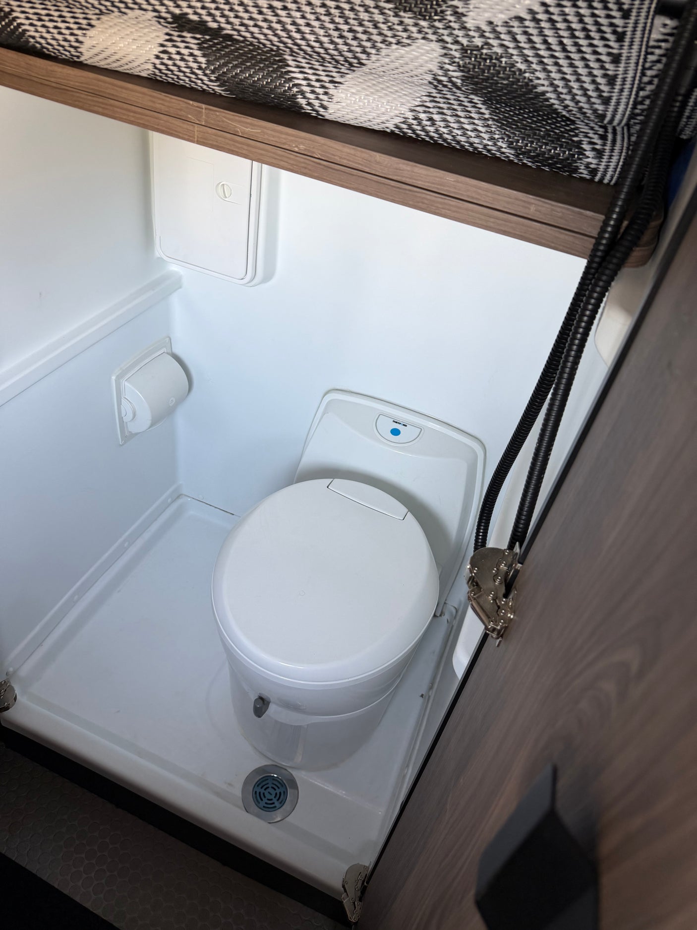 Inside an RV rental: a compact bathroom featuring a toilet, shower pan, and functional design.