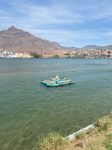Person relaxes on paddleboards in clear water, with mountains & homes nearby. An ideal spot for your next RV rental trip!