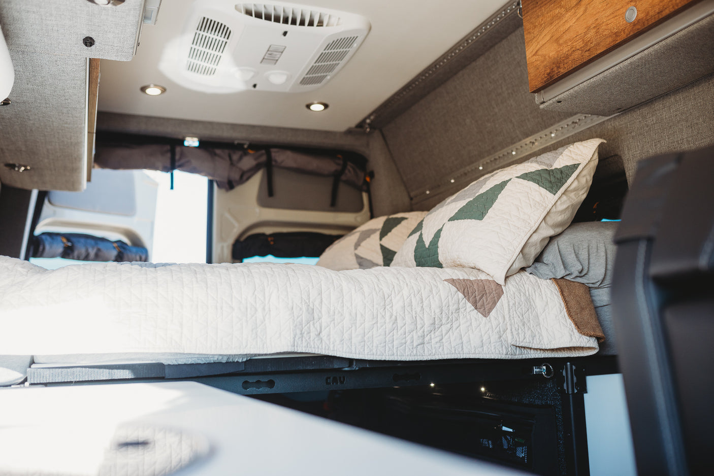This RV rental features a comfy sleeping area with quilted bedding, overhead AC, and integrated storage.