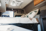 This RV rental features a comfy sleeping area with quilted bedding, overhead AC, and integrated storage.