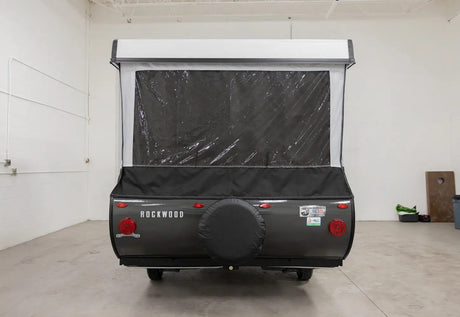 Rear view of a Rockwood pop-up RV rental with its extended canvas top, clear window, and spare tire. Ready for camping adventures.