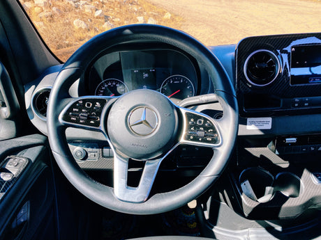 Interior of a Mercedes-Benz RV rental, showing the modern dashboard, steering wheel, and climate controls on a sunny day.