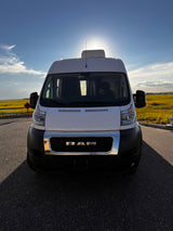 Front view of a white Ram ProMaster van, perfect for an RV rental adventure, parked against a sunny, golden field.