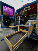 RV rental: Inside a customized camper van with a pull-out kitchen, storage, and cozy wooden interior, ready for adventure.