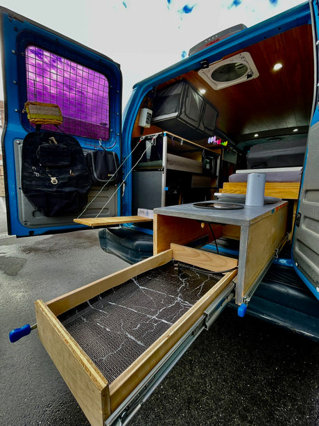 RV rental: Inside a customized camper van with a pull-out kitchen, storage, and cozy wooden interior, ready for adventure.