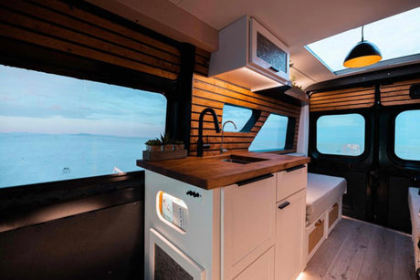 RV rental: Inside a modern camper van with a cozy kitchenette, wood details, and panoramic views for comfortable mobile living.
