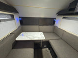 Modern RV rental dinette featuring comfortable U-shaped seating, a stylish marble table, and soft blue lighting.