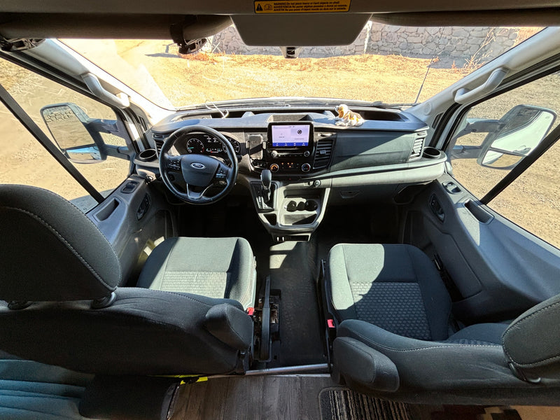 RV rental interior: View of a Ford van's cockpit from the rear, showing the dashboard, steering wheel, and front seats. — photo 6