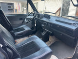 RV rental interior: driver's view of a classic camper van with dark seats, steering wheel, and dashboard.