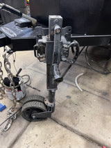 RV rental trailer's front hitch assembly: jack with wheels, safety chains, and electrical unit. Essential for towing.