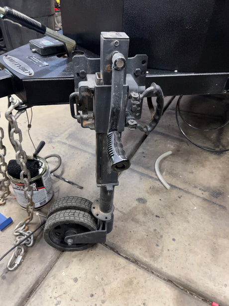 RV rental trailer's front hitch assembly: jack with wheels, safety chains, and electrical unit. Essential for towing.