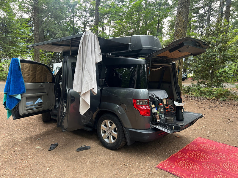 A grey Honda Element, set up like an RV rental for car camping, features an awning, cargo box, and a rear kitchen station. — photo 14
