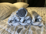 Plush pillows and rolled, striped blankets on patterned bedding in an RV rental. A cozy sleep setup.